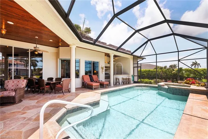 View of pool featuring a patio, a ceiling fan, a pool with connected hot tub, and glass enclosure