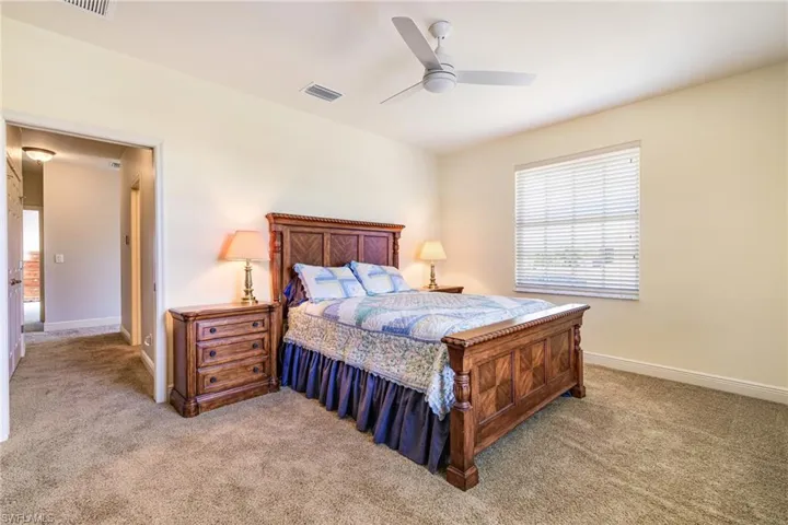Bedroom featuring light colored carpet, baseboards, and a ceiling fan