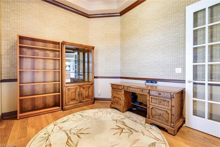 Office featuring wallpapered walls, wood finished floors, baseboards, crown molding, and wainscoting