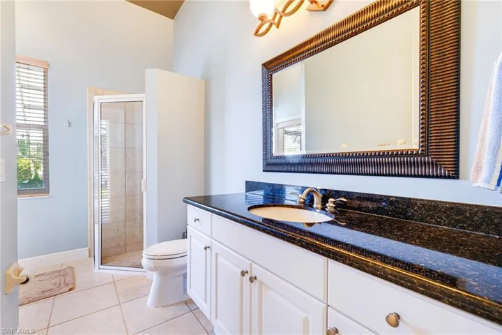 Bathroom with toilet, vanity, a stall shower, tile patterned floors, and baseboards