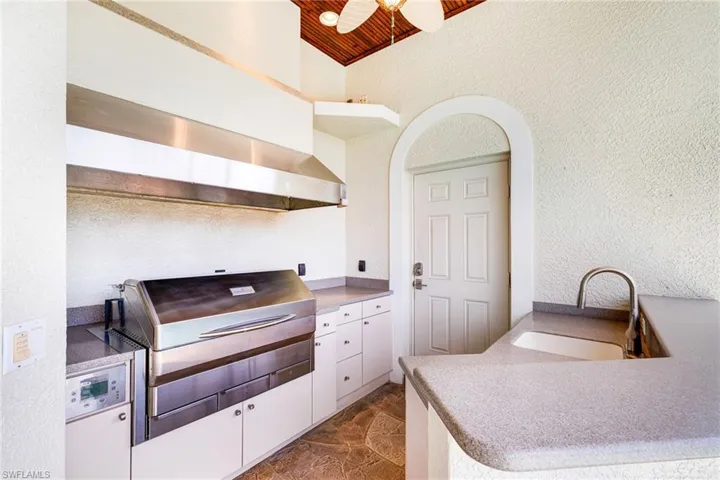 Kitchen featuring a sink, a textured wall, white cabinets, ceiling fan, and open shelves