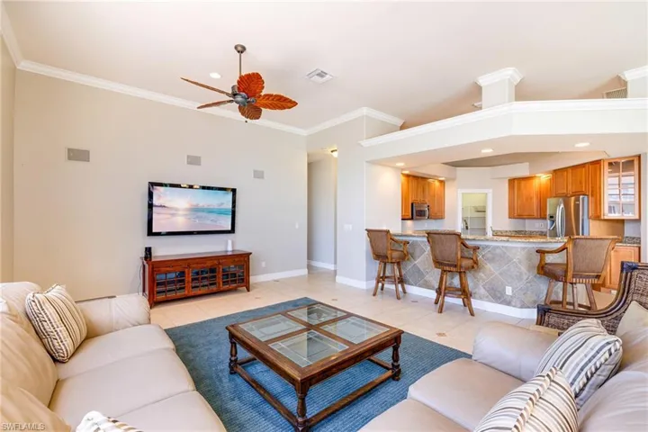 Living room with a ceiling fan, crown molding, light tile patterned floors, baseboards, and recessed lighting