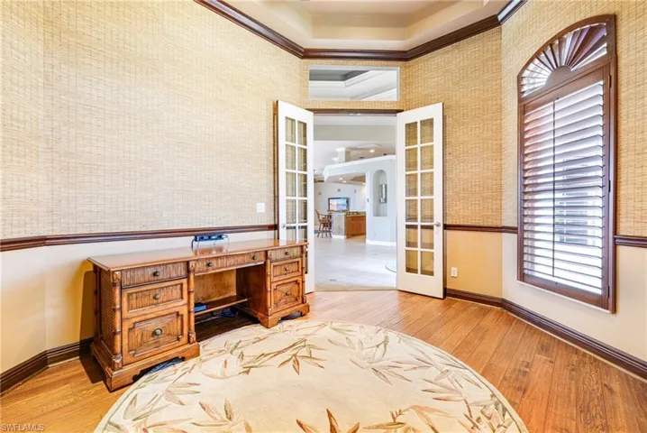 Home office with french doors, wallpapered walls, baseboards, light wood-style floors, and ornamental molding