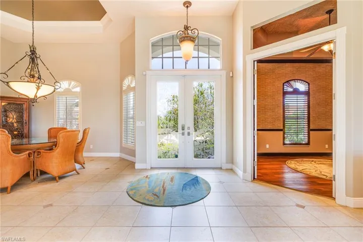 Tiled foyer featuring french doors, baseboards, a high ceiling, and ornamental molding