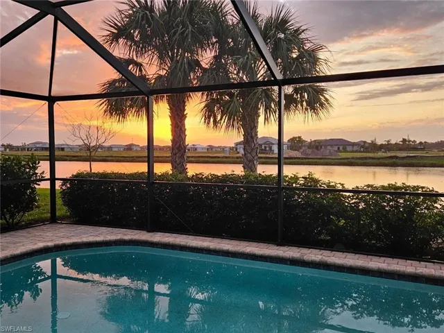 Pool at dusk featuring a water view and a lanai