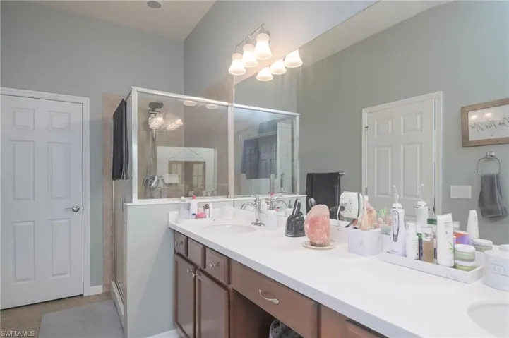 Bathroom featuring walk in shower, double vanity, and tile patterned floors