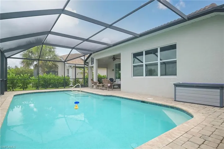 View of pool featuring a patio area, ceiling fan, and glass enclosure