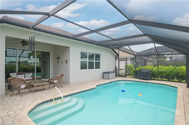 View of pool with a patio area, ceiling fan, and glass enclosure