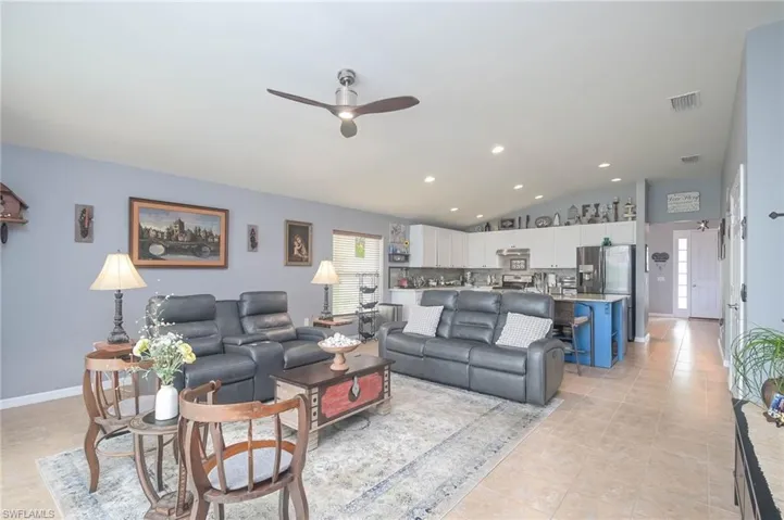 Living room featuring lofted ceiling, light tile patterned floors, and ceiling fan