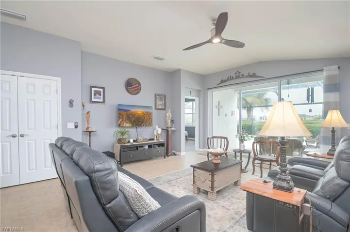 Tiled living room with ceiling fan and vaulted ceiling