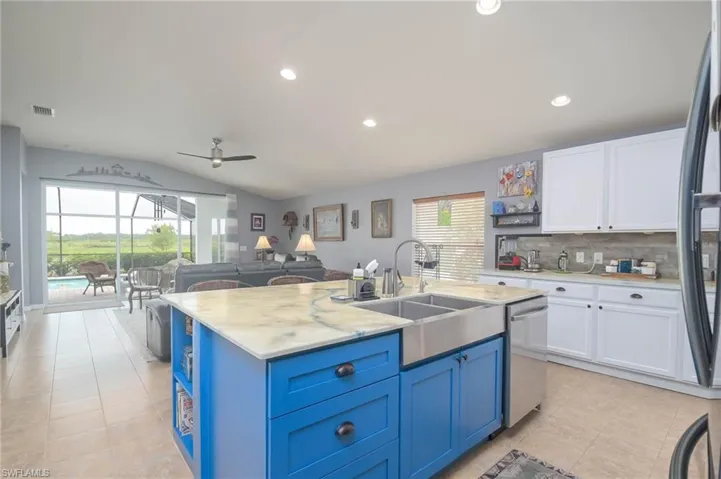 Kitchen with white cabinets, an island with sink, blue cabinetry, and stainless steel dishwasher