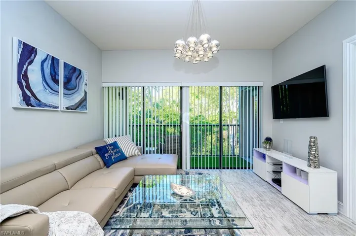 Living area with plenty of natural light, a chandelier, and light wood-style floors