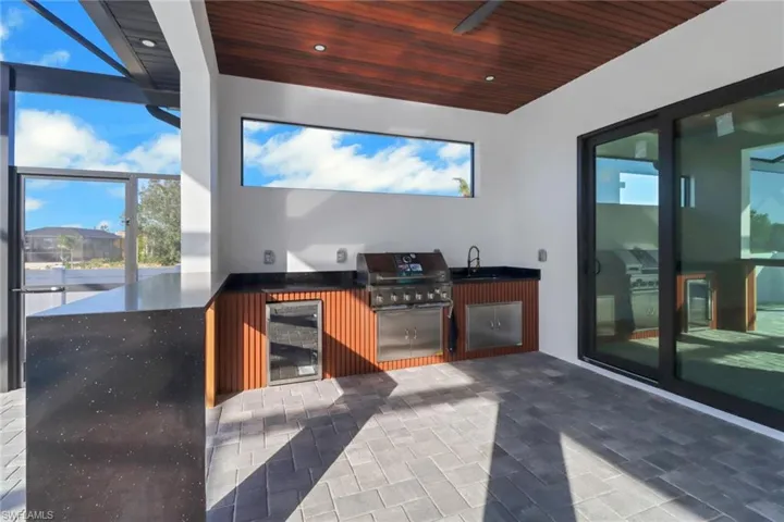 Summer kitchen with stainless appliances and granite bar.