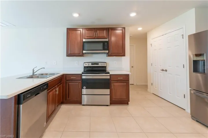 Kitchen with kitchen peninsula, sink, light tile patterned floors, and stainless steel appliances