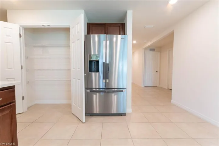 Kitchen featuring light tile patterned flooring and stainless steel fridge