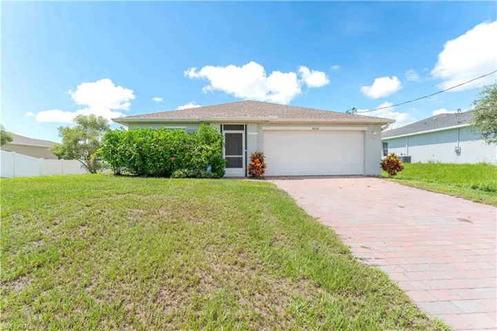 Ranch-style home with a garage and a ront lawn