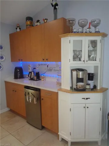 Kitchen featuring white cabinets, dishwasher, light tile patterned flooring, and glass insert cabinets