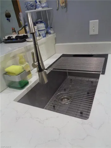 Kitchen view of light stone counters and a sink