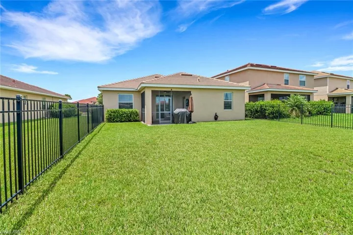 Back of property featuring a fenced backyard, a tile roof, stucco siding, and a yard