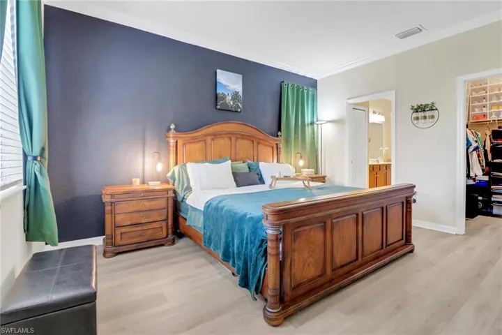 Bedroom with baseboards, a closet, a walk in closet, and light wood-type flooring