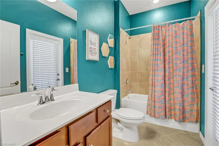 Full bathroom with tile patterned floors, toilet, vanity, shower / bath combo, and a textured wall