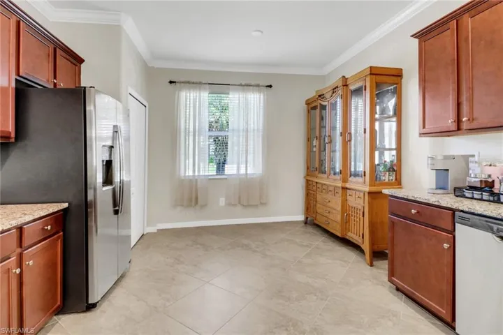 Kitchen with baseboards, stainless steel appliances, crown molding, and light stone counters