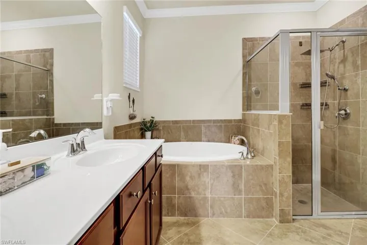 Bathroom featuring vanity, crown molding, a stall shower, and a garden tub