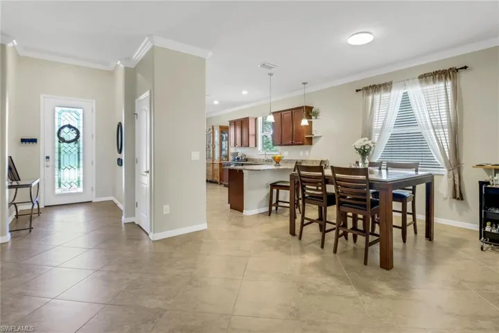 Dining area featuring light tile patterned floors, plenty of natural light, crown molding, and baseboards