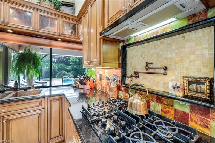 Kitchen with decorative backsplash, dark stone counters, black gas cooktop, and sink