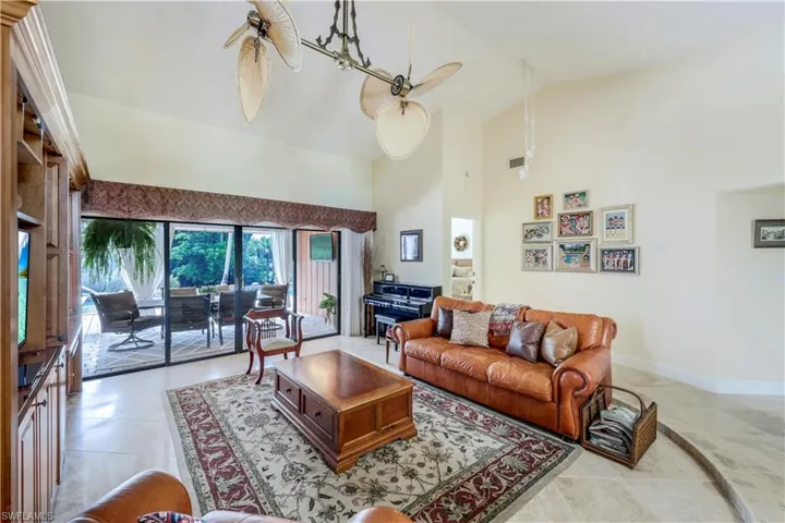 Tiled living room featuring high vaulted ceiling and ceiling fan