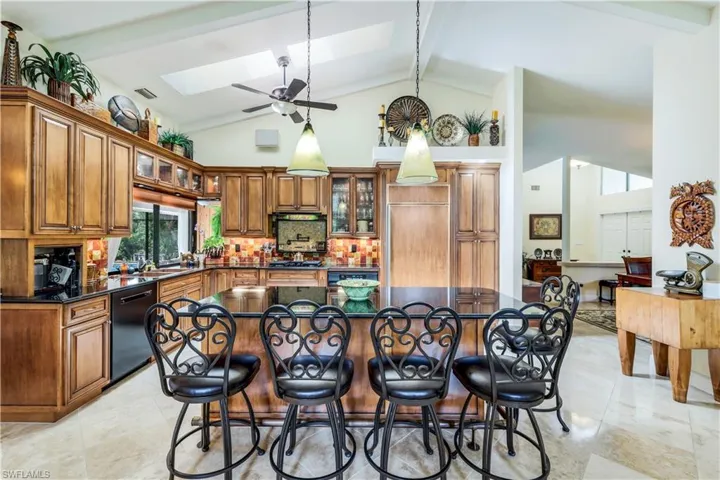 Kitchen featuring a kitchen bar, light tile patterned floors, a skylight, and beam ceiling