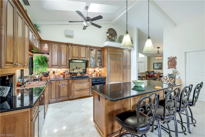 Kitchen featuring high vaulted ceiling, beamed ceiling, a kitchen island, light tile patterned floors, and a kitchen breakfast bar