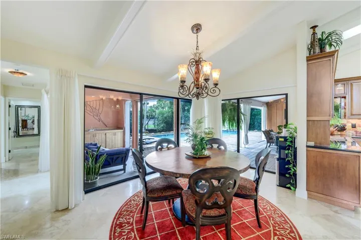 Dining space featuring vaulted ceiling with beams, an inviting chandelier, a healthy amount of sunlight, and light tile patterned floors