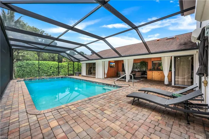 View of pool with glass enclosure and a patio area