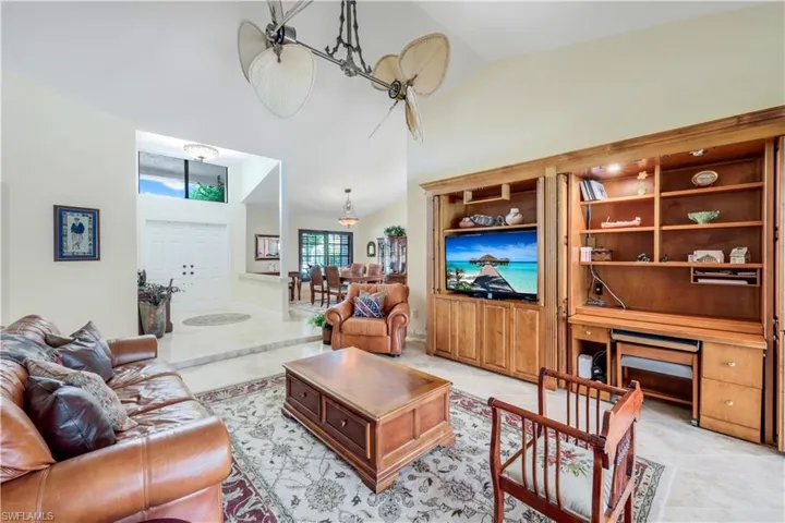 Tiled living room featuring high vaulted ceiling