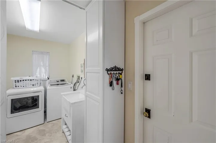 Laundry area with washer and clothes dryer and light tile patterned floors