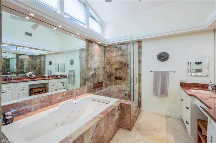 Bathroom with vanity, plus walk in shower, tile patterned flooring, and high vaulted ceiling