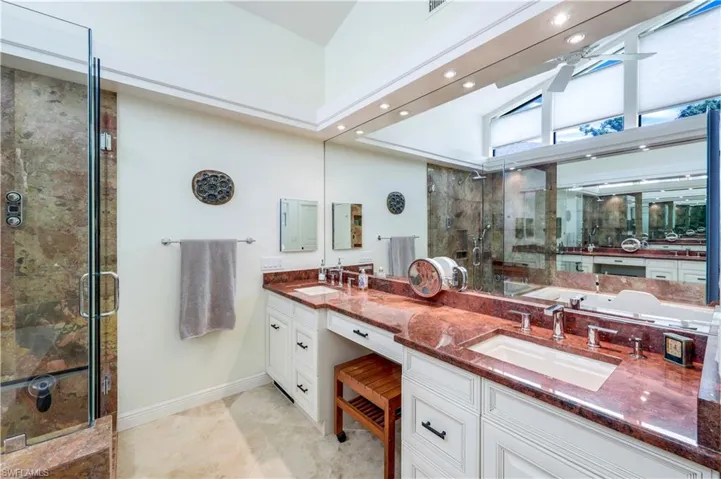 Bathroom with vaulted ceiling, double vanity, tile patterned flooring, separate shower and tub, and ceiling fan