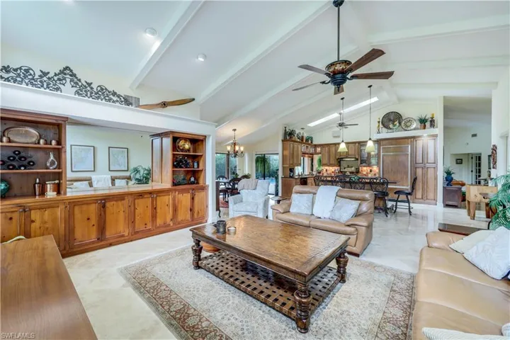 Living room featuring high vaulted ceiling, beamed ceiling, ceiling fan with notable chandelier, and light tile patterned floors
