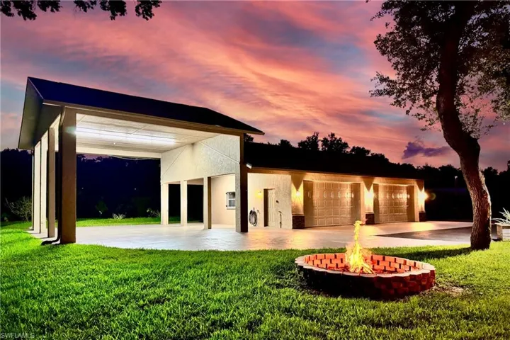 Back house at dusk featuring a yard and a garage