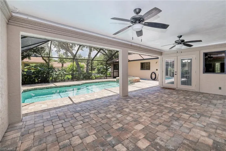 View of pool featuring glass enclosure, french doors, a patio, and ceiling fan
