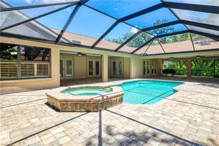 View of pool featuring glass enclosure, ceiling fan, french doors, and a patio
