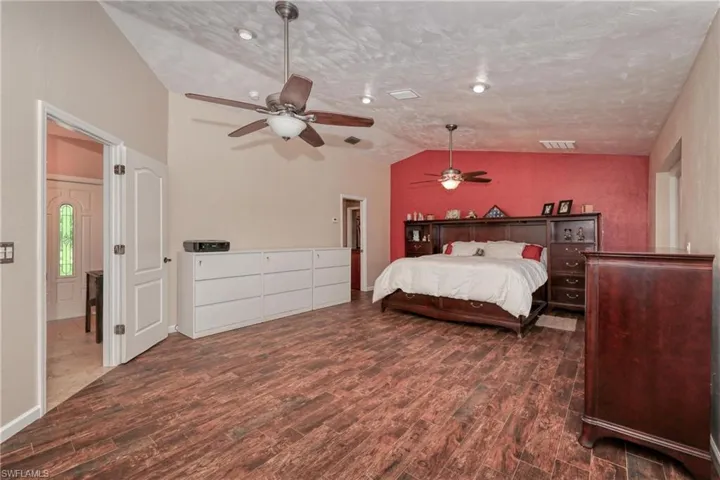 Bedroom featuring ceiling fan, a textured ceiling, hardwood / wood-style floors, and lofted ceiling