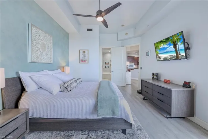 Bedroom with ensuite bath, light wood-type flooring, and ceiling fan