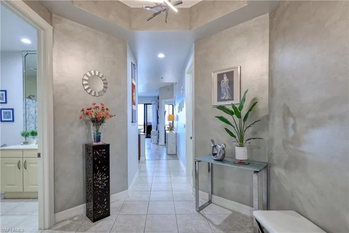 Hallway featuring light tile patterned flooring and a tray ceiling