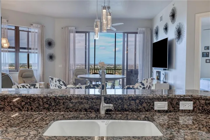 Kitchen with dark stone countertops, sink, and decorative light fixtures
