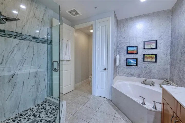 Full bathroom with independent shower and bath, toilet, vanity, and tile patterned flooring