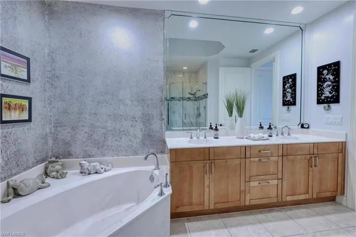 Bathroom with dual vanity, tile patterned floors, and plus walk in shower