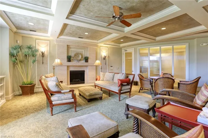 Living room featuring a fireplace, ceiling fan, ornamental molding, beam ceiling, and coffered ceiling
