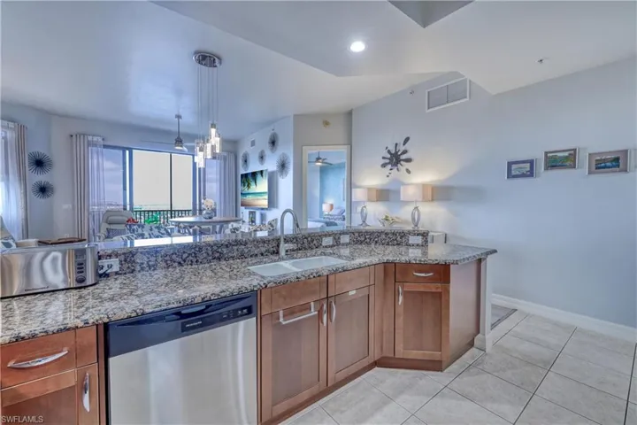 Kitchen with sink, light stone counters, stainless steel dishwasher, light tile patterned flooring, and ceiling fan